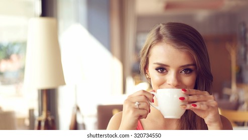 Close Up of Smiling Young Woman Sipping Coffee from White Mug in Sunny Window Seat of Trendy Cafe Restaurant with Copy Space - Powered by Shutterstock