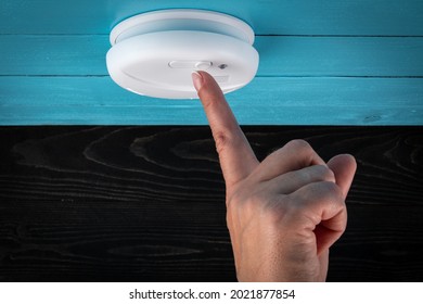 Close Up Smoke Detector On A Ceiling. Woman's Finger Presses The Test Button. Smoke, Fire Alarm.