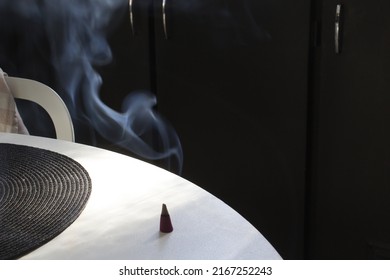 Close Up Smoke Of Incense Cone On White Home Table On Black Background