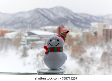 Close Up Of Snowman Toy With Blurred Background View Outside The Window Of Nakajima Park At Winter,snow Covered Ground In Sapporo,Hokkaido,Japan.