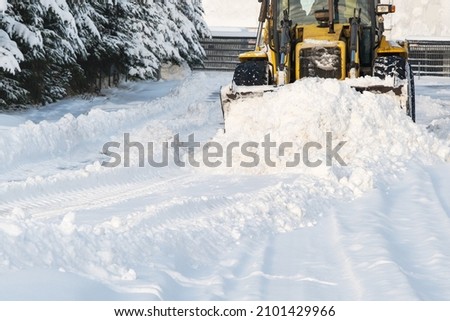 Close - up of snowplow plowing road during storm. Winter snow removal yellow large tractor. Removing snow in street after blizzard in Riga, Latvia