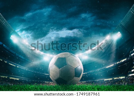 Close up of a soccer ball in the center of the stadium illuminated by the headlights
