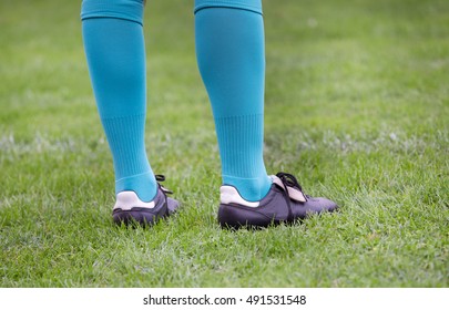 Close Up Of Soccer Player's Legs With Blue Socks And Football Boots Standing On Grass