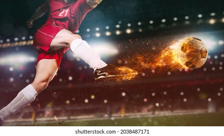 Close up of a soccer scene at night match with player in a red uniform kicking a fiery ball with power