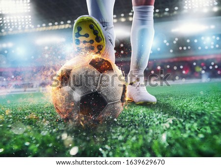 Close up of a soccer striker ready to kicks the fiery ball at the stadium