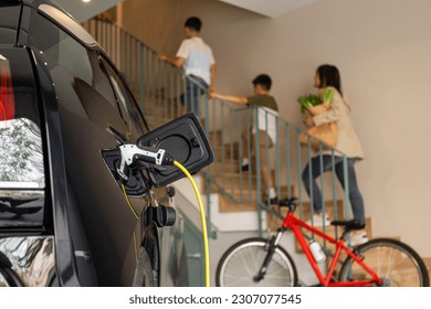 Close up of socket of electric vehicle charging in Home Electric Station while Unrecognizable family climb the stairs at home. Energy Conscious, Sustainable Resources. Blur background, Horizontal - Powered by Shutterstock