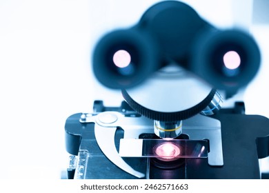 Close up and soft focus glasse slide and out of focus objective lens microscope in laboratory.Examining histological sample, a biopsy in the laboratory of cancer research.Medical patholology.