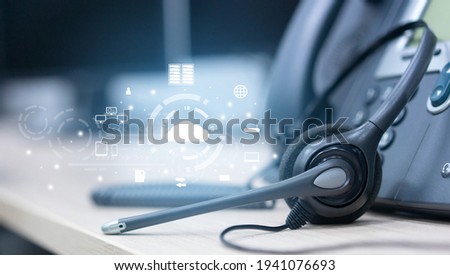 close up soft focus on headset with telephone devices at office desk for customer service support with Saas technology communication icon concept