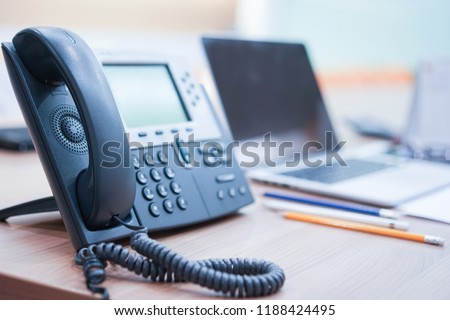 
close up soft focus on telephone devices with notebook stationary at office desk with light effect,communication technology concept
