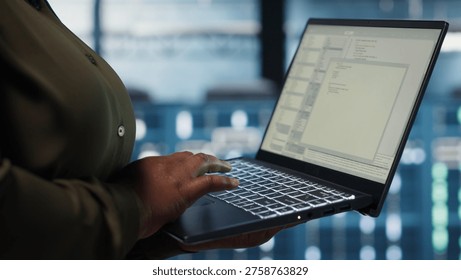 Close up of software developer working in data center to optimize network infrastructure. Programmer in server farm diagnosing and resolving equipment malfunctions using device - Powered by Shutterstock - Get 15% off with code: PIKWIZARD15