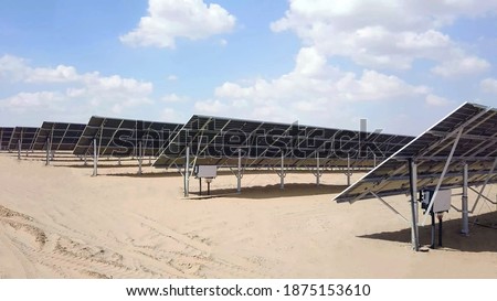 close up of solar power panels in desert with view of distribution board with cloudy sky in background. photovoltaic PV modules in a Solar energy plant farm.
