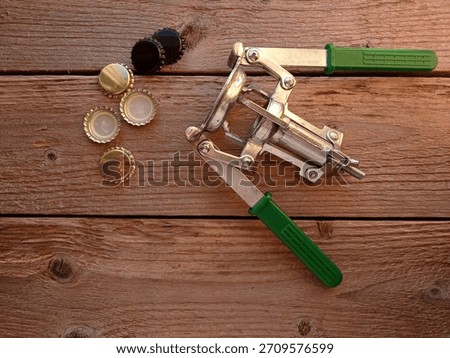 Close up of some crown corks and a manual crown capper on a wooden table.