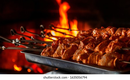 Close up of some meat skewers grilled in a barbecue. Barbecue grill, seasoned meat strung on skewers against the backdrop of the fire of a blazing fireplace in an expensive natural food restaurant - Shutterstock ID 1635056794