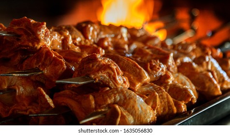 Close up of some meat skewers grilled in a barbecue. Barbecue grill, seasoned meat strung on skewers against the backdrop of the fire of a blazing fireplace in an expensive natural food restaurant - Shutterstock ID 1635056830
