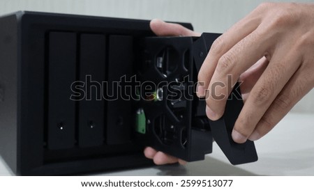 close up of someone's hand inserting a hard disk into a Network Attached Storage
