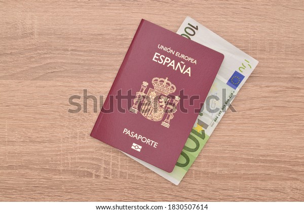 Close up Spain Passport with One Hundred Euro\
Paper Currency on wood grain\
table
