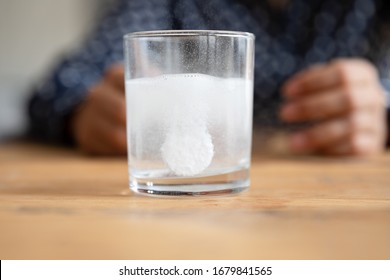 Close Up Sparkling Water Glass With Dissolving Effervescent Aspirin Pill Standing On Wooden Table, Sick Unhealthy Woman Taking Emergency Medicine, Painkiller To Relieve Headache Or Fever