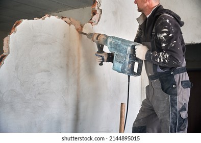 Close up of special powerful hand instrument with percussion mechanism for drilling and breaking walls. Man holding jackhammer and dismantling inner wall in room.