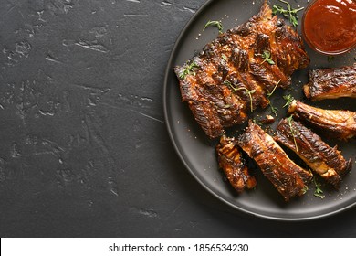 Close up of spicy grilled spare ribs on plate over dark stone background with copy space. Top view, flat lay