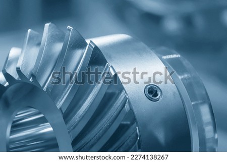 Close up  the spiral bevel gear part in the light blue scene. The high precision mechanical parts manufacturing concept.