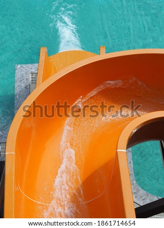 Close up splash water in orange slider at waterpark in hot summer day.
