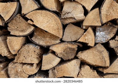 Close up of split firewood stacked together, showing natural wood grain, bark texture and freshly cut surfaces.