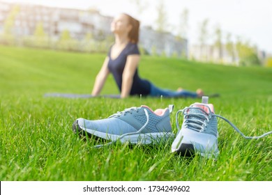 Close up sports shoes sneakers on green grass and Yoga girl on background. Sports in the open air.