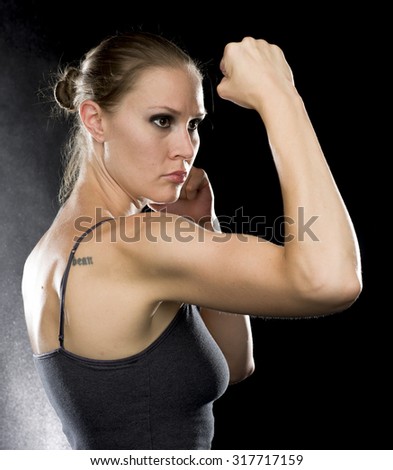 Similar – Close up front portrait of one young athletic woman in sportswear in gym over dark background, standing in boxing stance with hands and fists, looking at camera