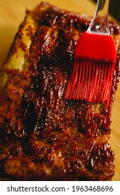 Close Up Of Spreading Barbecue Sauce On Homemade Pork Ribs Barbecue By Using A Silicone Rubber Brush. 