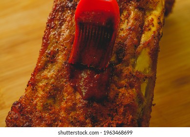 Close Up Of Spreading Barbecue Sauce On Homemade Pork Ribs Barbecue By Using A Silicone Rubber Brush. 