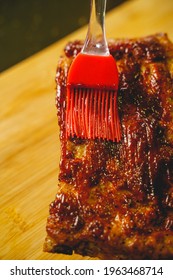 Close Up Of Spreading Barbecue Sauce On Homemade Pork Ribs Barbecue By Using A Silicone Rubber Brush. 