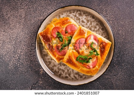Close up of square mini pizza with tomato, sausage and cheese on a plate for a snack top view