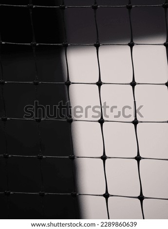 close up of squares on plastic fence against white and black background of wall shadows and shapes in back geometric shapes squares lines and angles textured shaped background backdrop fence wallpaper