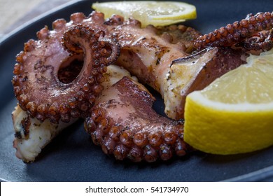 Close Up Squid Tentacles With Lemon On Black Plate