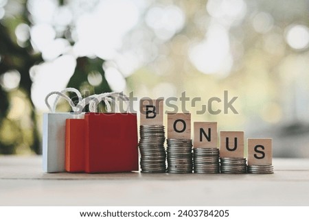 close up stack of coin, bonus wooden text block and small shopping bag on wood table, saving and manage money to success business, holiday season and Boxing Day sale concept