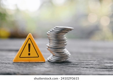 close up stack of coin and caution sign on wood table, saving and manage money to success business, economic crisis risk and problem concept