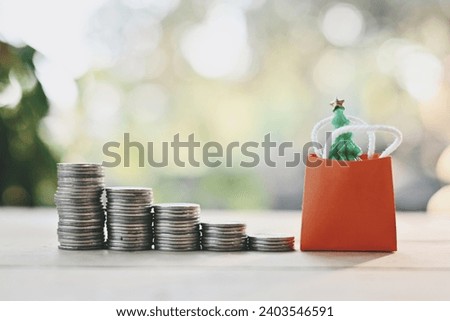 close up stack of coin, small shopping bag with snowman and pine tree on wood table, saving and manage money for holiday season, merry Christmas and happy new year, Boxing Day sale concept