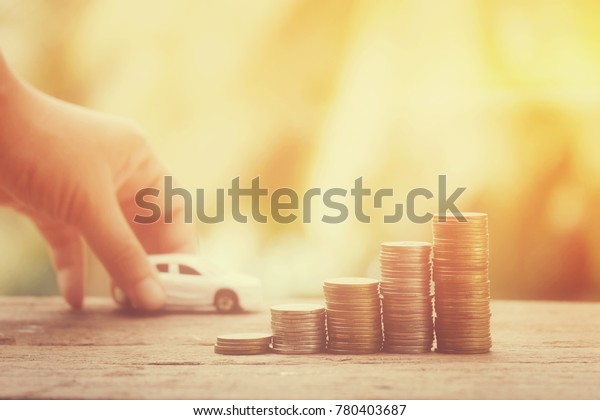 close up stack of\
coins on old wood table with hand holding toy car background,\
saving money for transport and manage for success business concept,\
process vintage tone