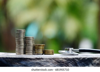 close up stack of coins and stethoscope on old wood table with nature copy space background, business and healthcare concept