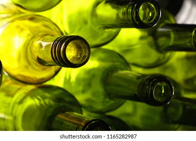 Close up stack of five empty washed green glass wine bottle necks, low angle side view