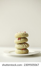 Close up of stack of homemade mint gingerbread cookies with matcha, decorated sublimated strawberries and vanilla cream on plate on white background. Sugar, gluten and lactose free and vegan