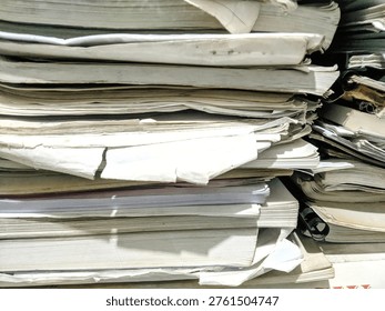 Close up stack of messy old papers and books in a storage room, concept of bureaucracy, archives, and recycling.