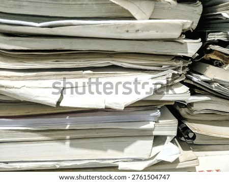 Close up stack of messy old papers and books in a storage room, concept of bureaucracy, archives, and recycling.