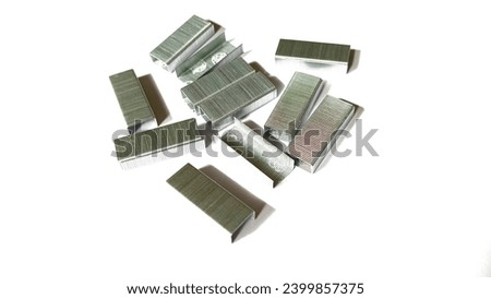 Close up of stack of metal staples, isolated on white background, selective focus. 