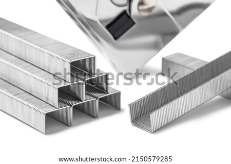 Close up of stack of metal staples for stapler gun isolated on white background, selective focus. Industrial tool.