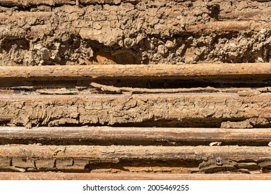 The close up of a stack of old rusty dirty used wrecked U metal beam retrieving from demolished apartment building with soil and sand pieces during hard light of sunny day background material texture
