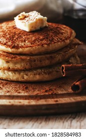 close up of a stack of pancakes and butter on a rustic board