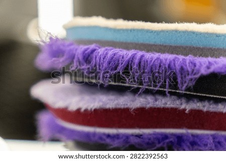 Close up of a stack of professional car detailing buffing pads. Multicolored wool and microfiber polishing wheels for electric dual action orbital machines in a garage auto workshop service station shop to restore paint gloss clearcoat surface.