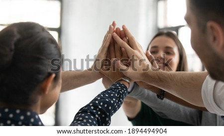Close up stacked palms of diverse business people gathered together in office celebrating successful project accomplishment, giving high five as symbol of trust, unity, support, team building concept