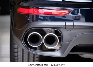 Close up of stainless steel exhaust tip muffler pipe of sports car. Dual exhaust at the back of black car with rear defuser. High performance cat-back reduce engine noise & increase engine power.